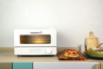 white modern design toaster oven is on the wooden table with pizza and homemade bread toast white...