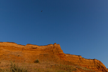 Fototapeta premium Geology. Desert landscape. Panorama view of the sandstone formation, the rocky cliffs, sand. Background or texture of sandy cliff on the coast, orange limestone