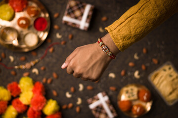 Raksha Bandhan background with an elegant Rakhi and Rice Grains on dark textured background.