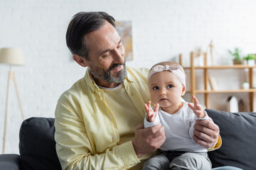 Positive mature man holding baby daughter