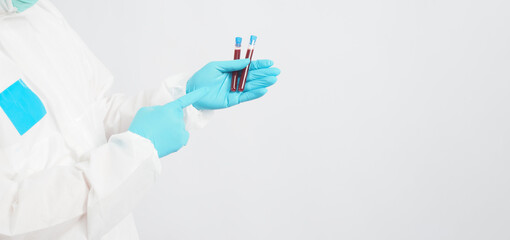 Hand with PPE suit and blue medical glove is holding blood test tube on white background.