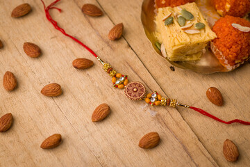 Raksha Bandhan background with an elegant Rakhi and Rice Grains on wooden textured background.