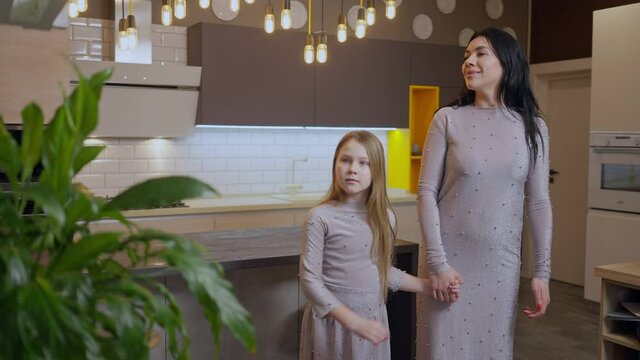 Beautiful Caucasian Mother And Pretty Daughter Admiring New Furniture In Shop Indoors. Portrait Of Confident Wealthy Woman And Girl In Similar Dresses Choosing Kitchen In Store. Slow Motion