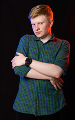 portrait of a red-haired guy in a green shirt and jeans on a black background.