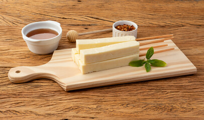 Rennet or Coalho cheese on a wooden board with sugar syrup and pepper