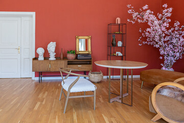 antique vintage interior in 19th century style living room with bright red walls, wood floor and direct sunlight inside the room.