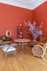 antique vintage interior in 19th century style living room with bright red walls, wood floor and direct sunlight inside the room.