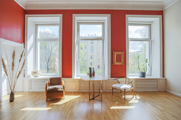 antique vintage interior in 19th century style living room with bright red walls, wood floor and direct sunlight inside the room.