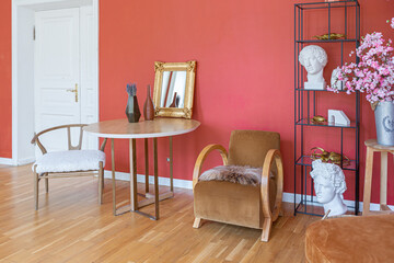 antique vintage interior in 19th century style living room with bright red walls, wood floor and direct sunlight inside the room.