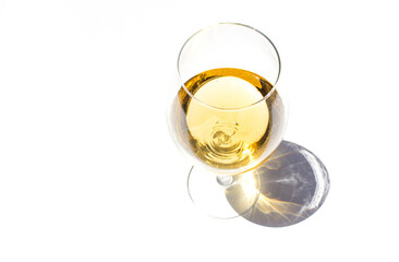 Top view of glass with white fresh wine on white background with sparkling shadows. Free copy...