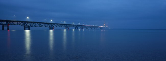 Michigans Mighty Mac the Mackinac Bridge connecting the Lower and Upper Peninsula photographed in fog during blue hour in a panoramic image