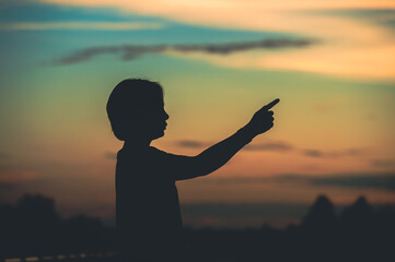 Fototapeta premium young woman pointing her hand aiming destination success at sunset.