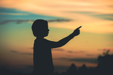 Fototapeta premium young woman pointing her hand aiming destination success at sunset.