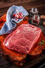 Raw marble denver beef on a wood resined cutting board with spices and rosemary