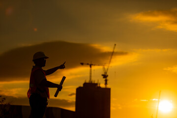 silhouette of engineer and construction site background at sunset