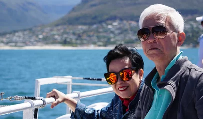 Fototapeten Asian senior elderly couple on tourist ferry boat to seals island trip attracion Fun wildlife watching aticity in South Africa trip © glowonconcept