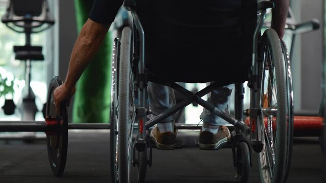 Old person with a disability at the gym preparing weights for exercise