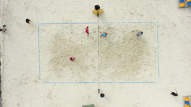 Top view of a group of friends playing beach volleyball on the beach