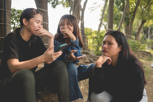 A young teenager woman cannot relate to a conversation her friends are having. Feeling awkward and out of place.