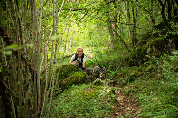 Naklejka na ściany i meble Blonde woman with two french bulldogs in the forest