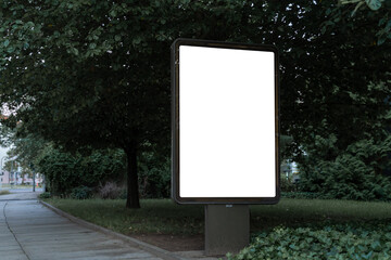 Advertising billboard panel for a mockup. Blank template for ads at a park with green trees. Space for an advertisement billboard at a park. White ad.