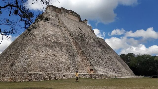 A photographer man walks alone against the background of the Mayan pyramid Uxmal. Slow motion