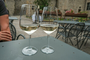 two glasses of white wine in restaurant on the tables across restaurant exterior. Restaurant terrace.