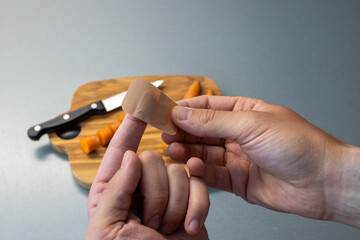 Close-up of a wound patch on a finger. cut into the finger while cooking. Care bloody wound at...
