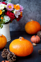 Pumpkins. Autumn creative flatlay, dark background with candles, autumn flowers, pine cones and pumpkins.