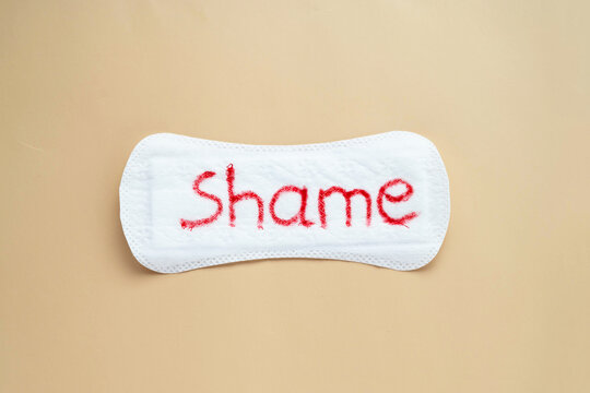 Woman's sanitary pad with word shame. Abstract social concept of shaming women for their menstrual period.