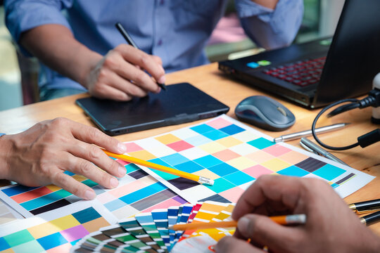 Interior designer chooses a color chart for home design. Graphic designers working on color chart at modern office.