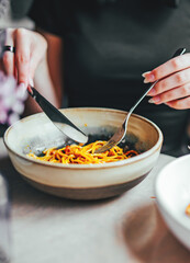 Italian food. woman hand holding fork and knife with spaghetti bolognese in bowl