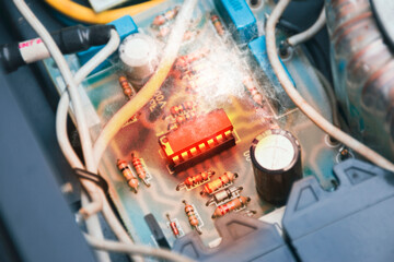 The Integrated circuit (IC) overheats and burns in the socket on the electronic circuit board - obrazy, fototapety, plakaty