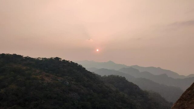 View of the sunset behind the mountains as seen from the Kumbhalgarh Fort in Udaipur, Rajasthan, India. 