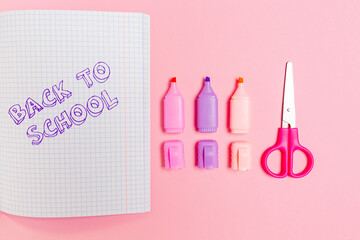 Back to school. Composition with opened copybook, markers and scissors on pink background. Flat lay. Concept of education and creativity