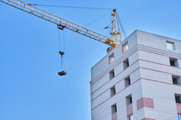 Construction site. Crane and multi-storey brick house against the blue sky. High quality photo