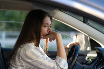 Drunk girl driving car. Unhappy young female sit on driver seat suffering from headache or...