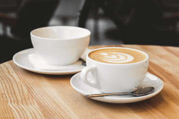 Cup of coffee with milk on wooden table. Hot Cappuccino or latte prepared with milk in coffee shop. Morning breakfast in cafe. Lifestyle