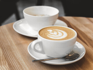 Cup of coffee with milk on wooden table. Hot Cappuccino or latte prepared with milk in coffee shop. Morning breakfast in cafe. Lifestyle