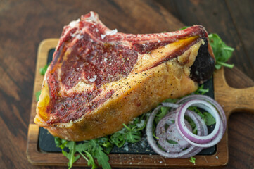  Delicious aged raw black angus beef steak ready-to-be-cooked on a wooden board with onion and rocket salad
