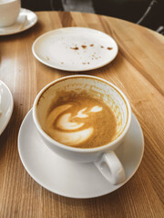 Cup of coffee with milk on wooden table. Hot Cappuccino or latte prepared with milk in coffee shop. Morning breakfast in cafe. Lifestyle
