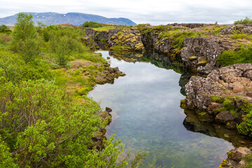 Fototapeta na wymiar Road near brown tectonic rock stone fault between Europe and America. Iceland