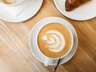 Cup of coffee with milk on wooden table. Hot Cappuccino or latte prepared with milk in coffee shop. Morning breakfast in cafe. Lifestyle. Flat lay