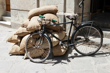 Fototapeta na wymiar Vintage bicycle leaning against a pile of burlap sacks on the street.