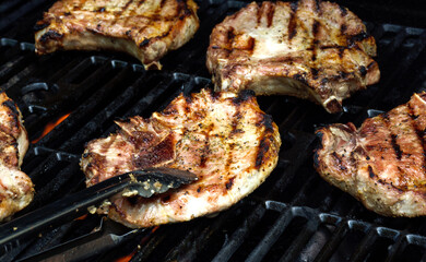 delicious grilled meat on barbecue grill with smoke and flames. Grilling pork outside. 