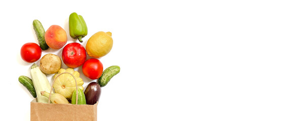 A paper shopping bag with vegetables and fruits, tomato, cucumber, squash, pepper, lemon, eggplant, zucchini, banana, apple, peach on white background