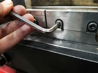 detail of a hand tightening or loosening a screw of a machine for tool change or machine...
