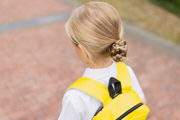 Naklejka premium Schoolgirl back to school after summer vacations. Child in uniform standing early morning outdoor. 