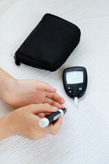 Child Hands Using Lancet on Finger to Check Blood Sugar Level by Glucometer.