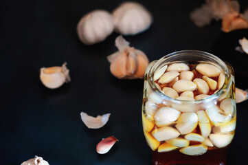 Fermented garlic cloves in a jar of honey, a rich source of  probiotics, over a rustic wood background table. Selective focus with blurred background and foreground